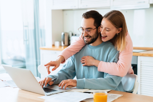 Happy couple reviewing their health insurance options in Ankeny, IA with Adamson Insurance & Associates on a laptop at home